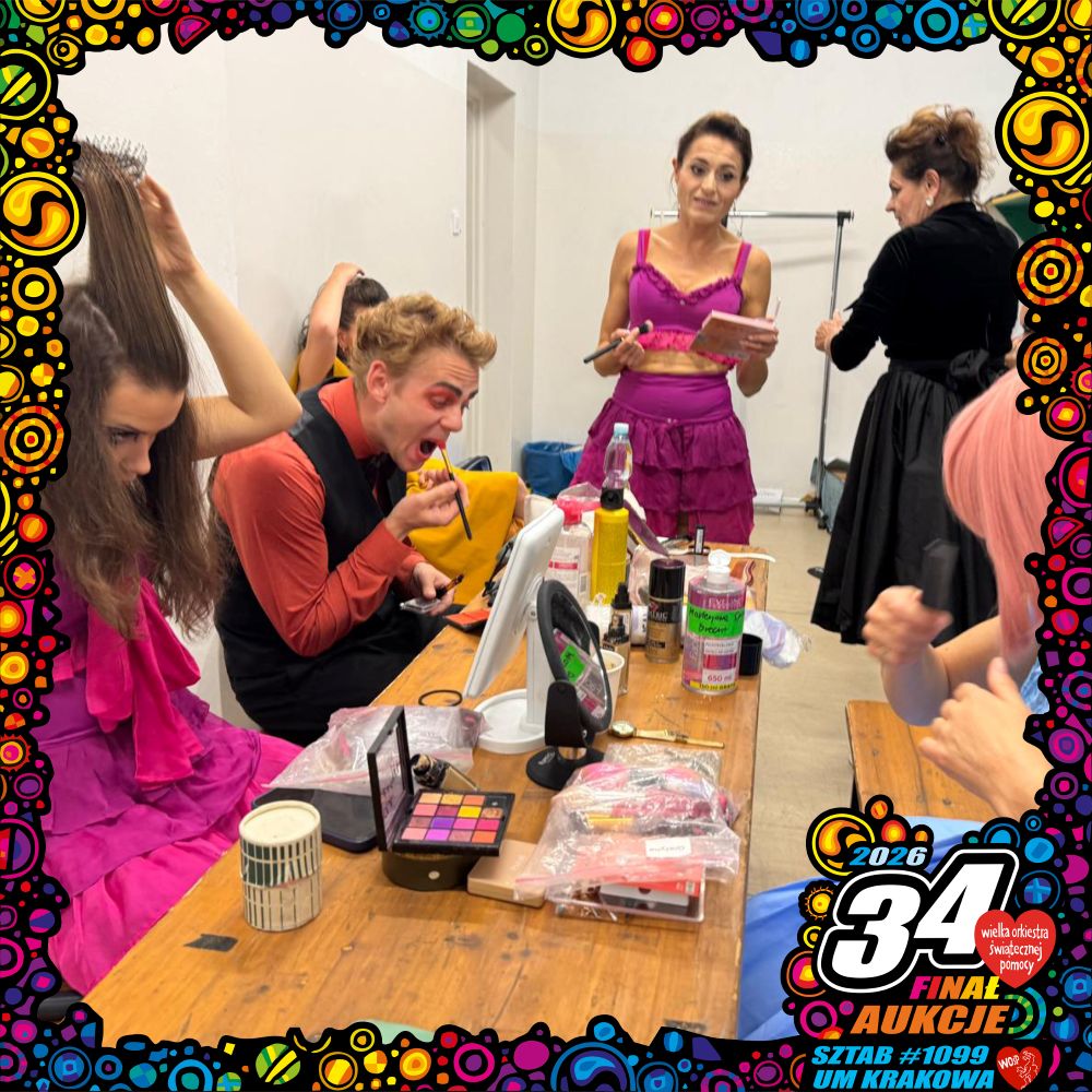 Cztery osoby w kolorowych strojach robią makijaż przy stole pokrytym kosmetykami przed spektaklem Bal. Kobieta w różu stoi czytając, podczas gdy inni siedzą nakładając makijaż. Zdjęcie zdobi żywa ramka i logo "34 Finału WOŚP".